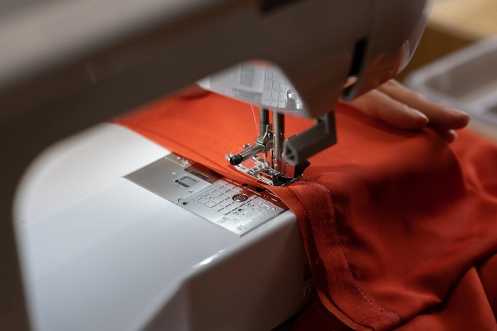 Close-up view of a sewing machine working on red fabric, representing craftsmanship.